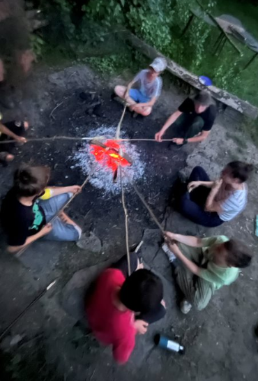 Hier sitzen wir in einem unserer wöchentlichen Treffen am Feuer und machen Stockbrot.